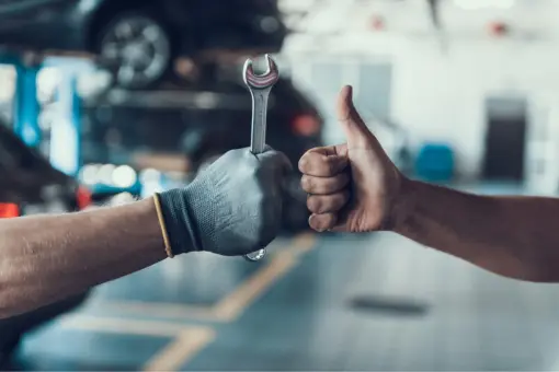 Bild von entgegenstreckenden Händen mit Gabelschlüssel und "Daumen hoch" symbolisiert unsere handwerkliche Kompetenz und Kundenzufriedenheit durch effiziente, schnelle und kostensparende Fahrzeuginstandsetzung